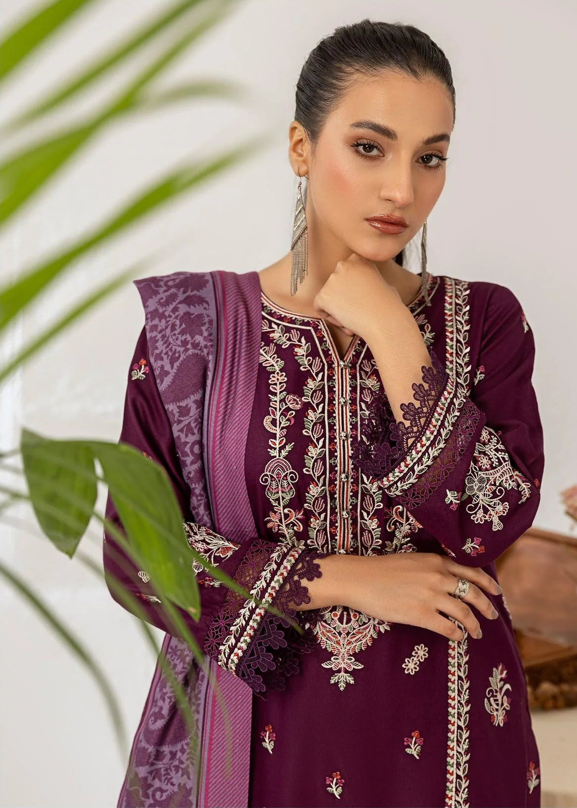 Woman wearing a purple embroidered outfit with a white background