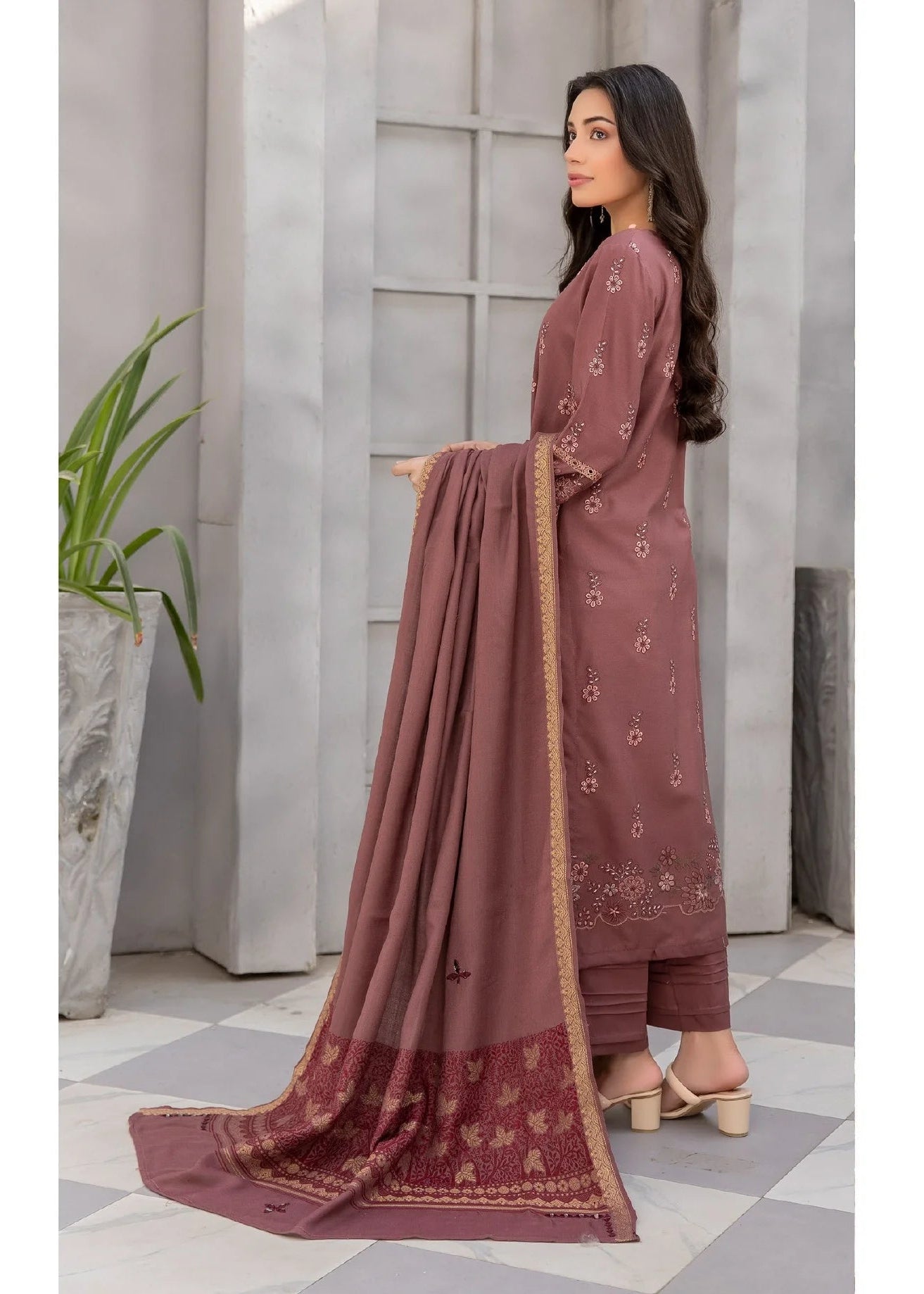 Woman wearing a maroon traditional outfit with a matching dupatta in an indoor setting.