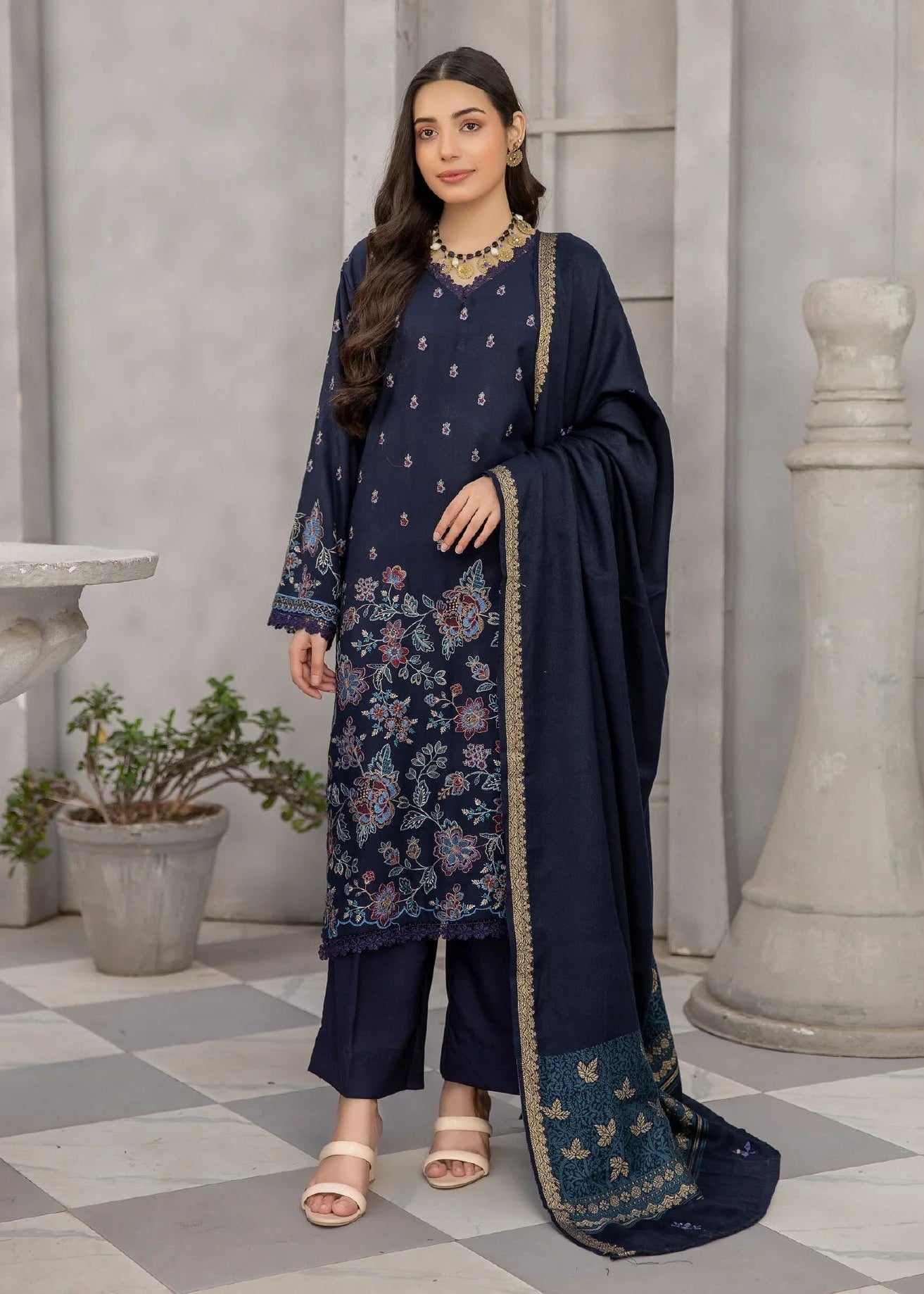Woman wearing a navy blue traditional outfit with a matching dupatta in an indoor setting.