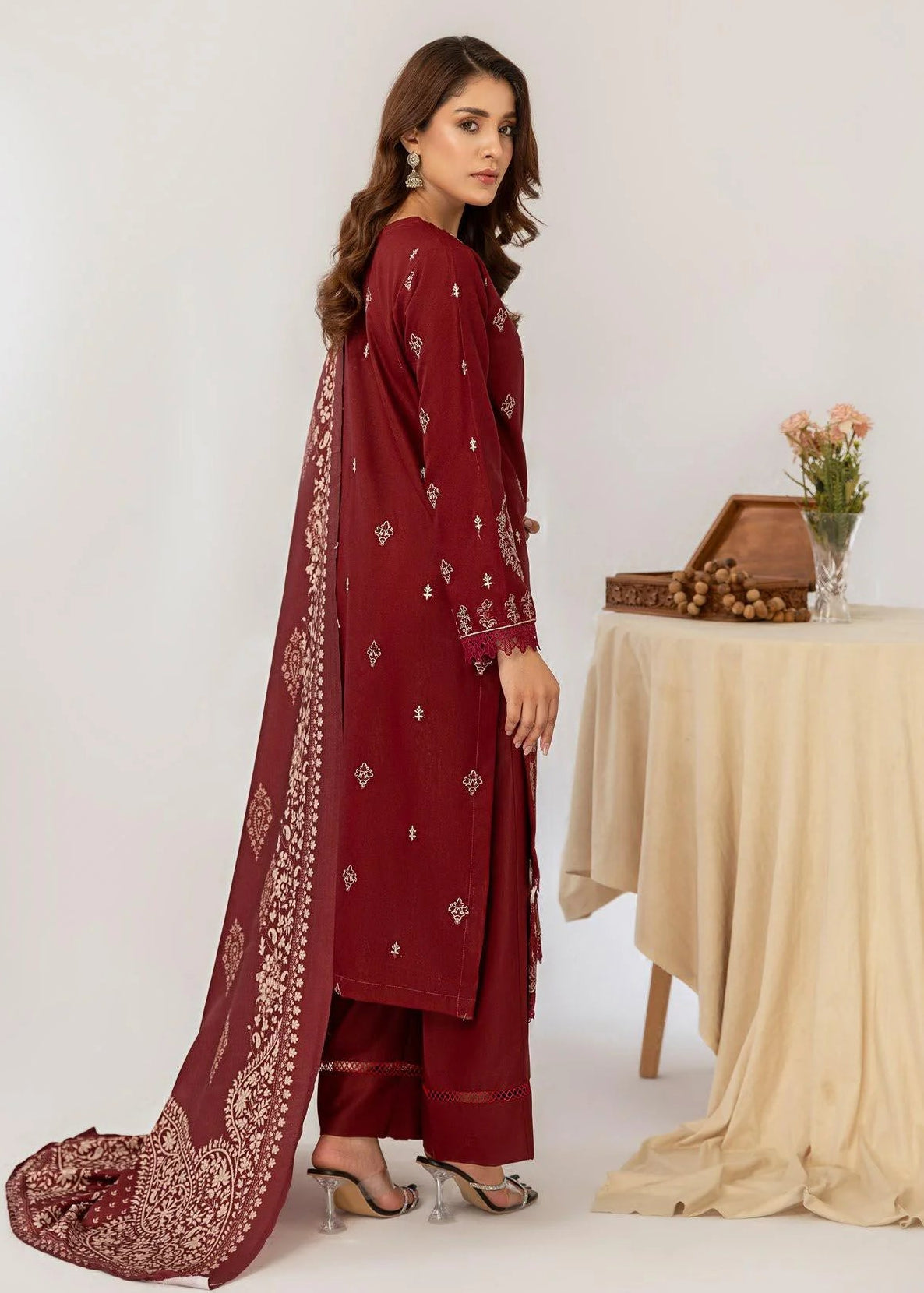 Woman wearing a maroon embroidered outfit with a matching dupatta on a white background.