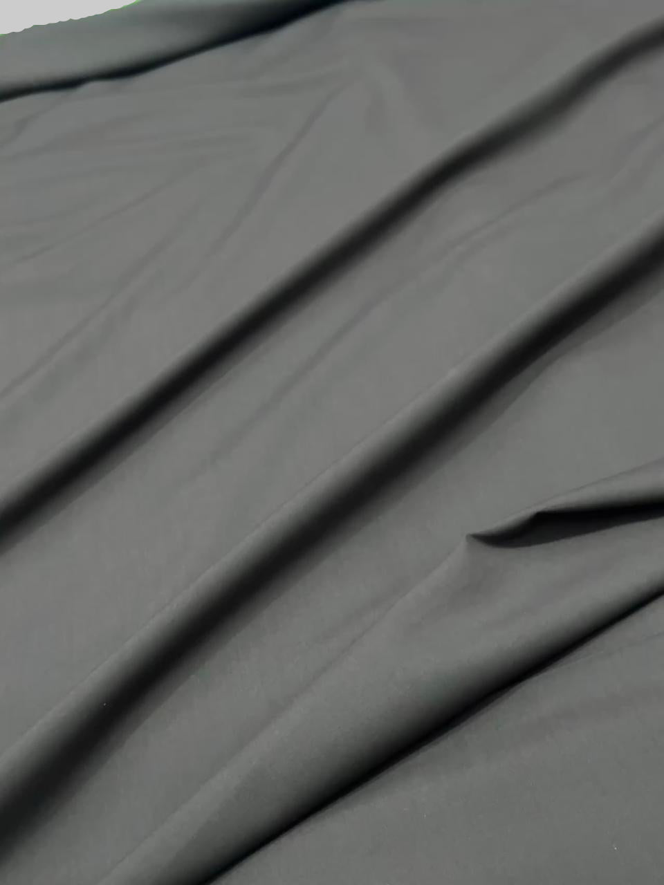 Dark gray fabric with folds on a plain background