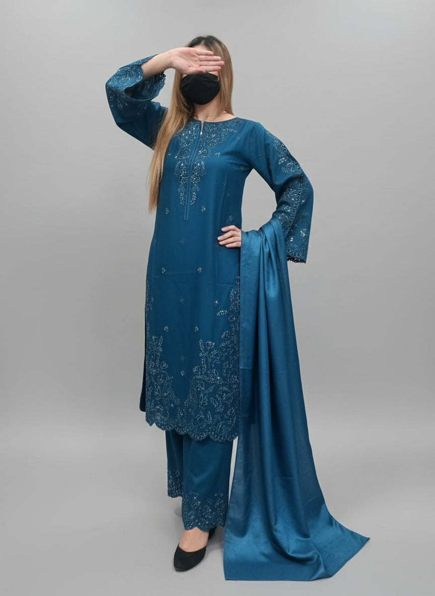 Woman wearing a blue dress with intricate designs in a green indoor setting