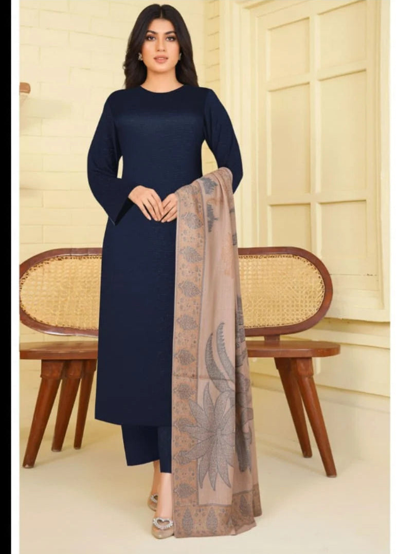 Woman wearing a navy blue outfit with a patterned scarf, standing in a room with wooden furniture.