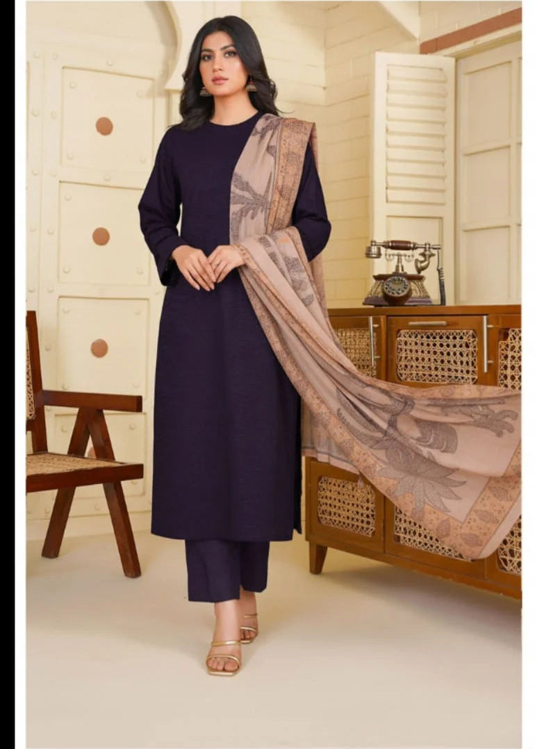 Woman in a dark blue outfit with a beige scarf standing in a room with wooden furniture.