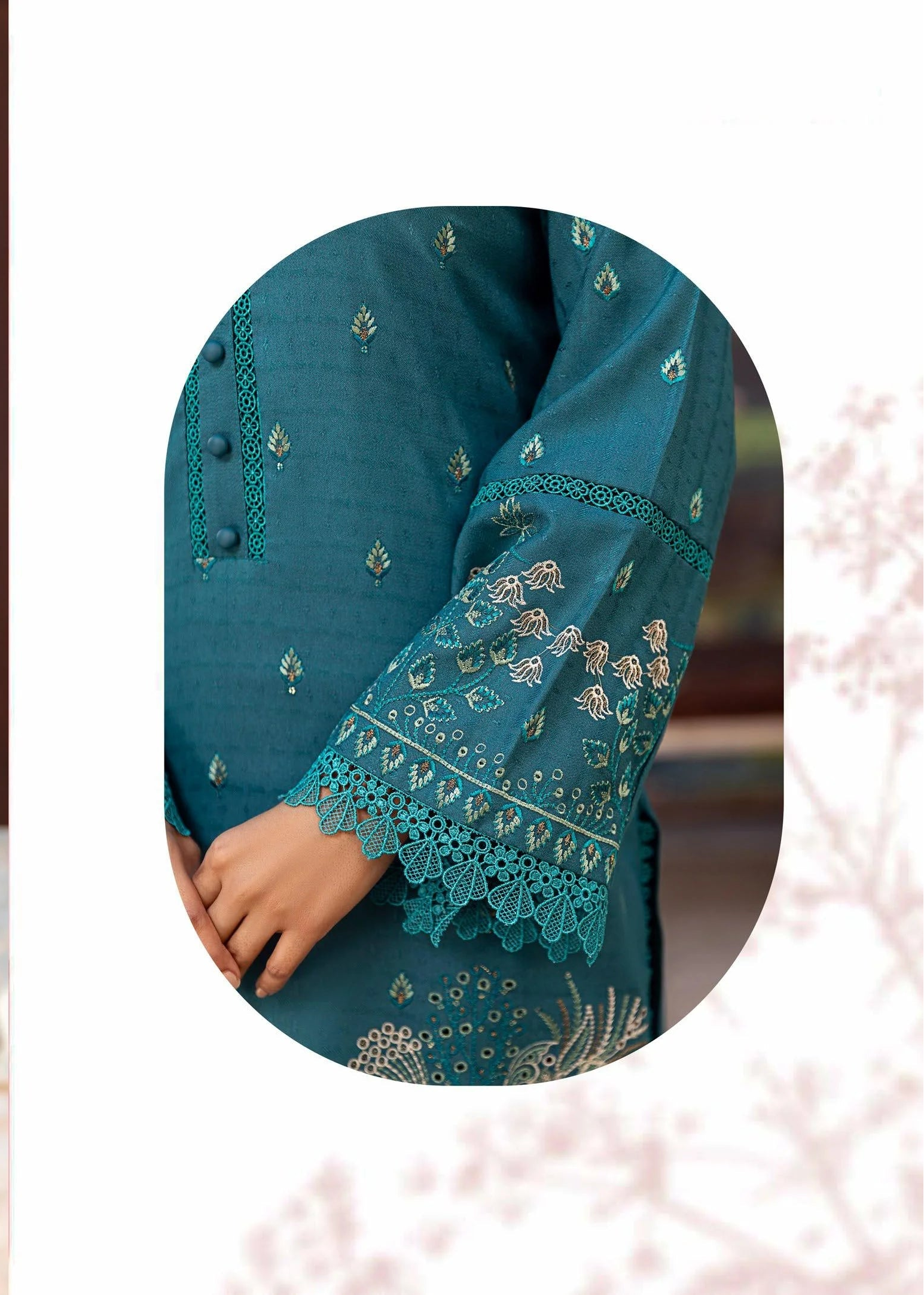 Woman wearing a teal embroidered outfit with a close-up of the fabric details.