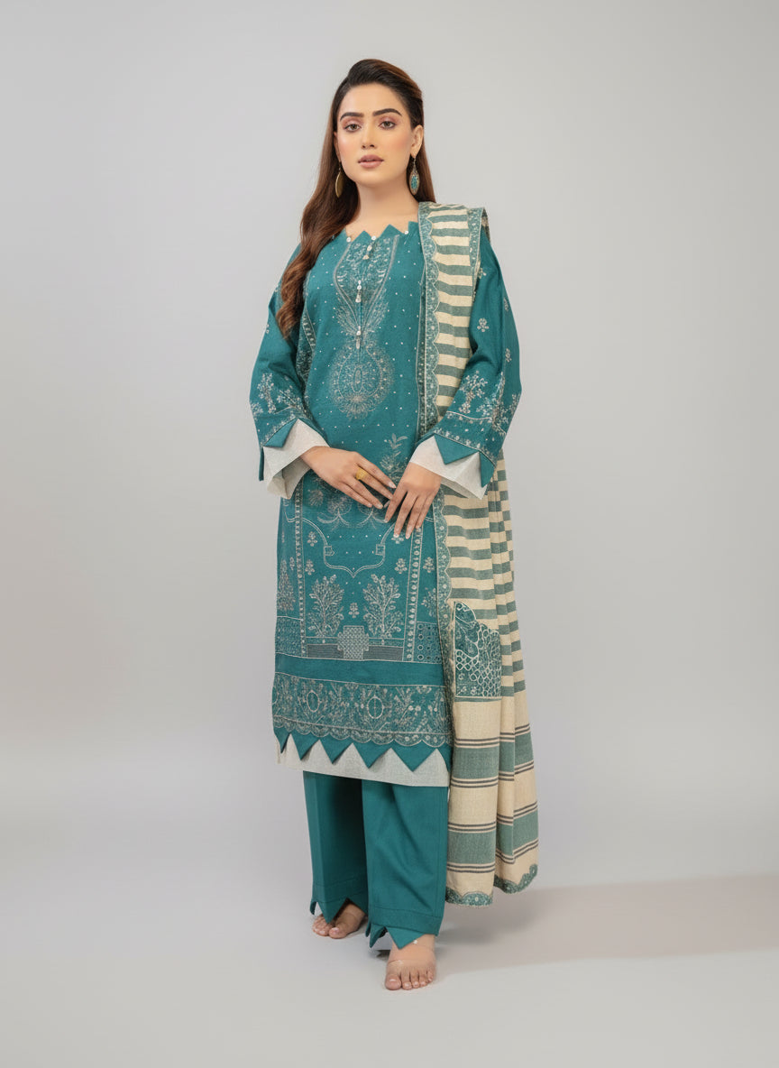 Woman in teal embroidered outfit with matching pants in a decorated room.