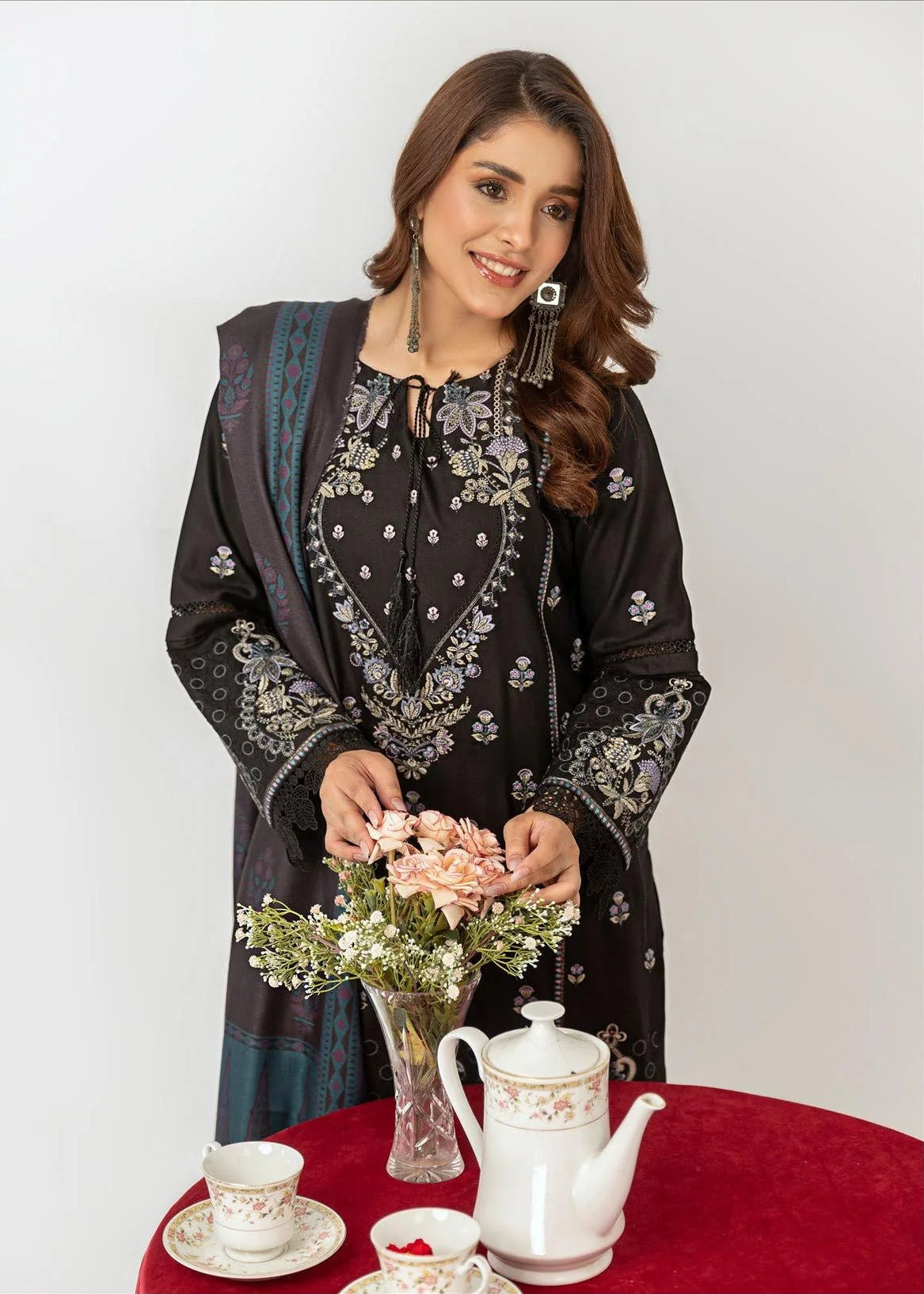 Woman in black and blue traditional outfit with a framed photo of herself at a tea party.