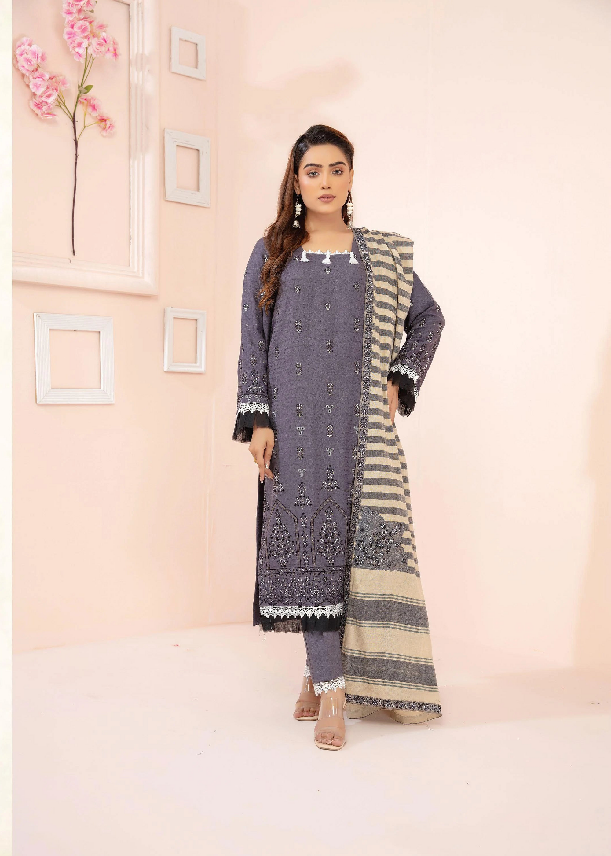 Woman wearing a gray and black patterned outfit with a matching jacket in a minimalistic setting.