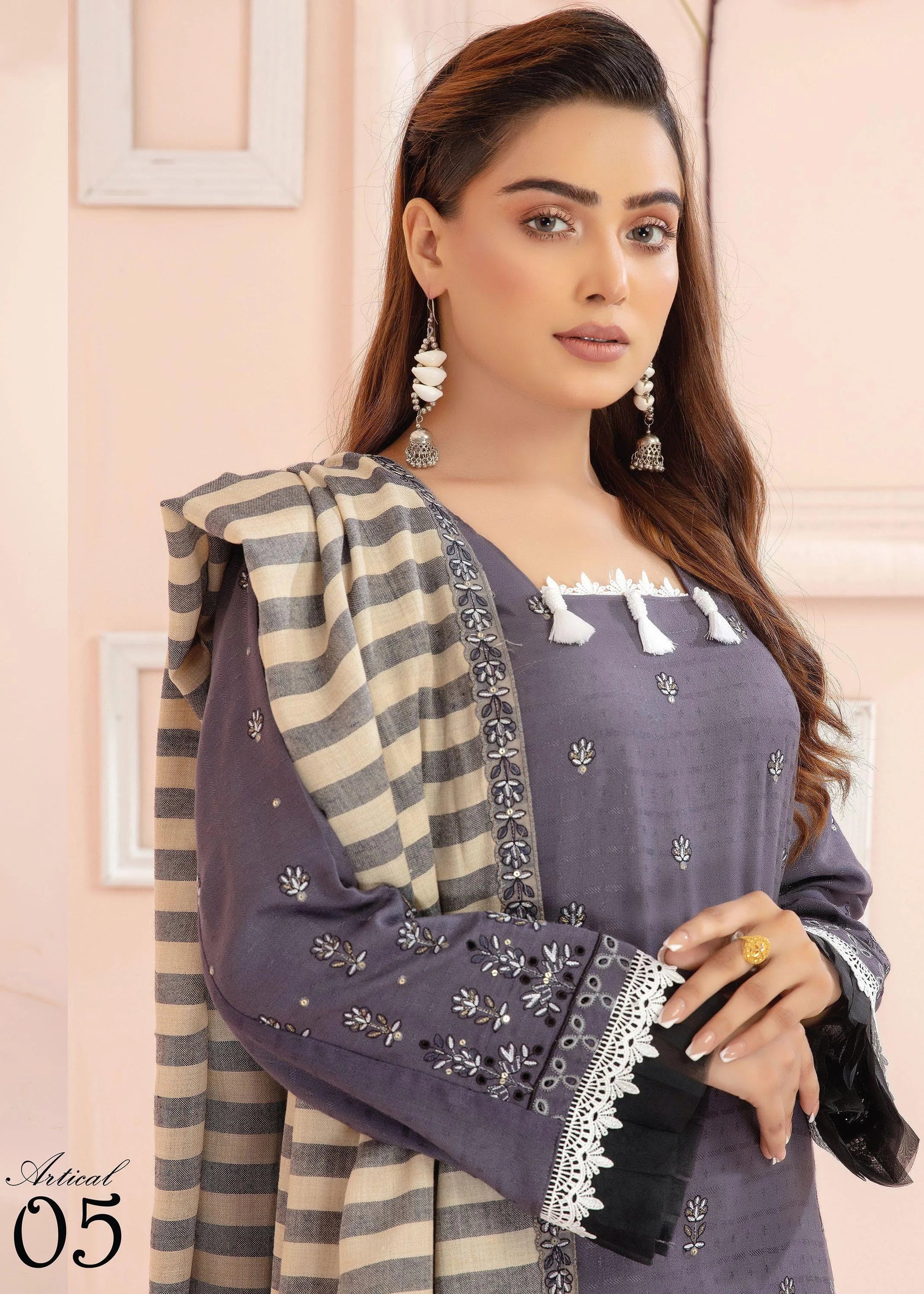 Two women wearing matching outfits with a striped shawl against a light pink background.