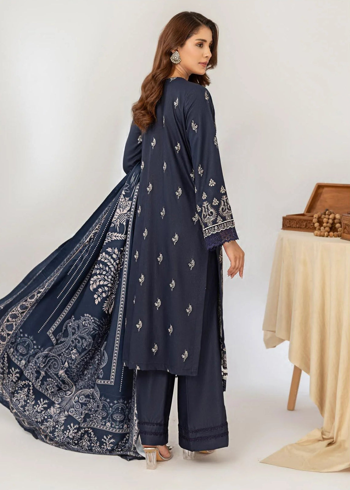 Woman wearing a navy blue embroidered outfit with a matching dupatta on a white background