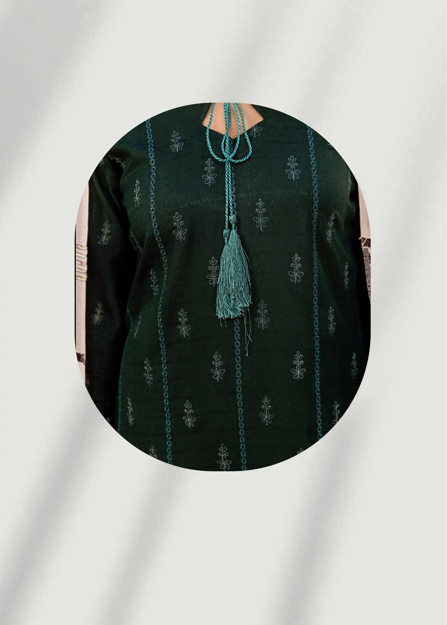 Woman wearing a dark green embroidered outfit with a close-up of the fabric texture.