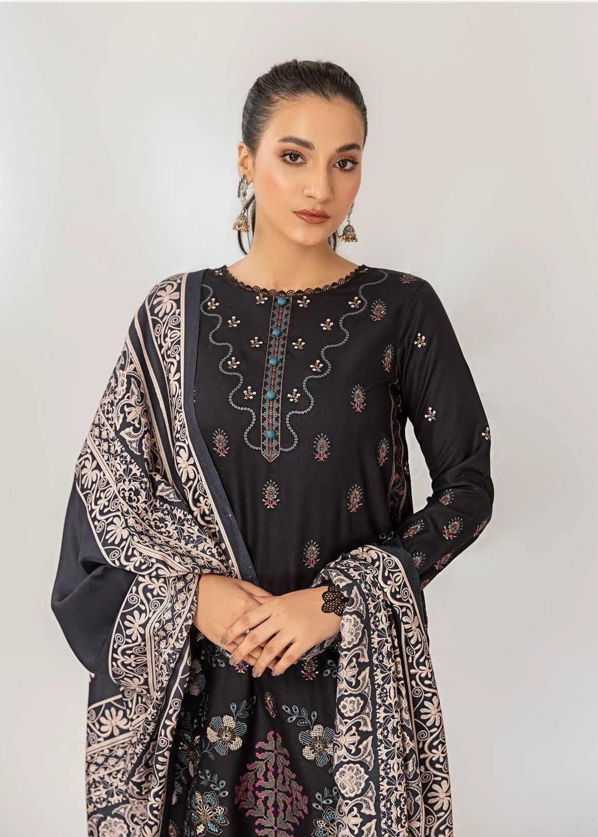 Woman wearing a black embroidered outfit with a patterned dupatta on a white background