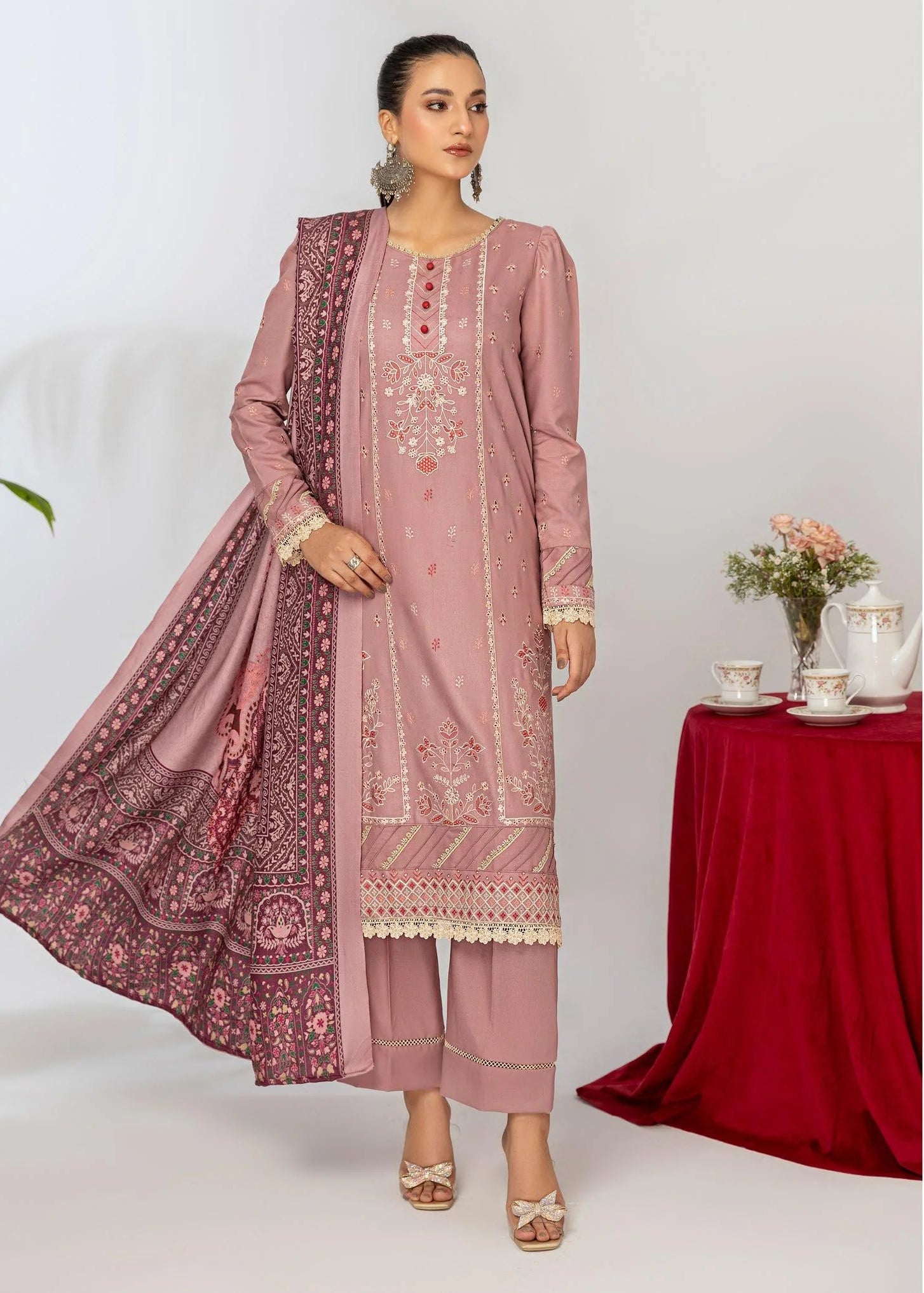Woman wearing a pink traditional outfit with a matching dupatta, standing in front of a white background.