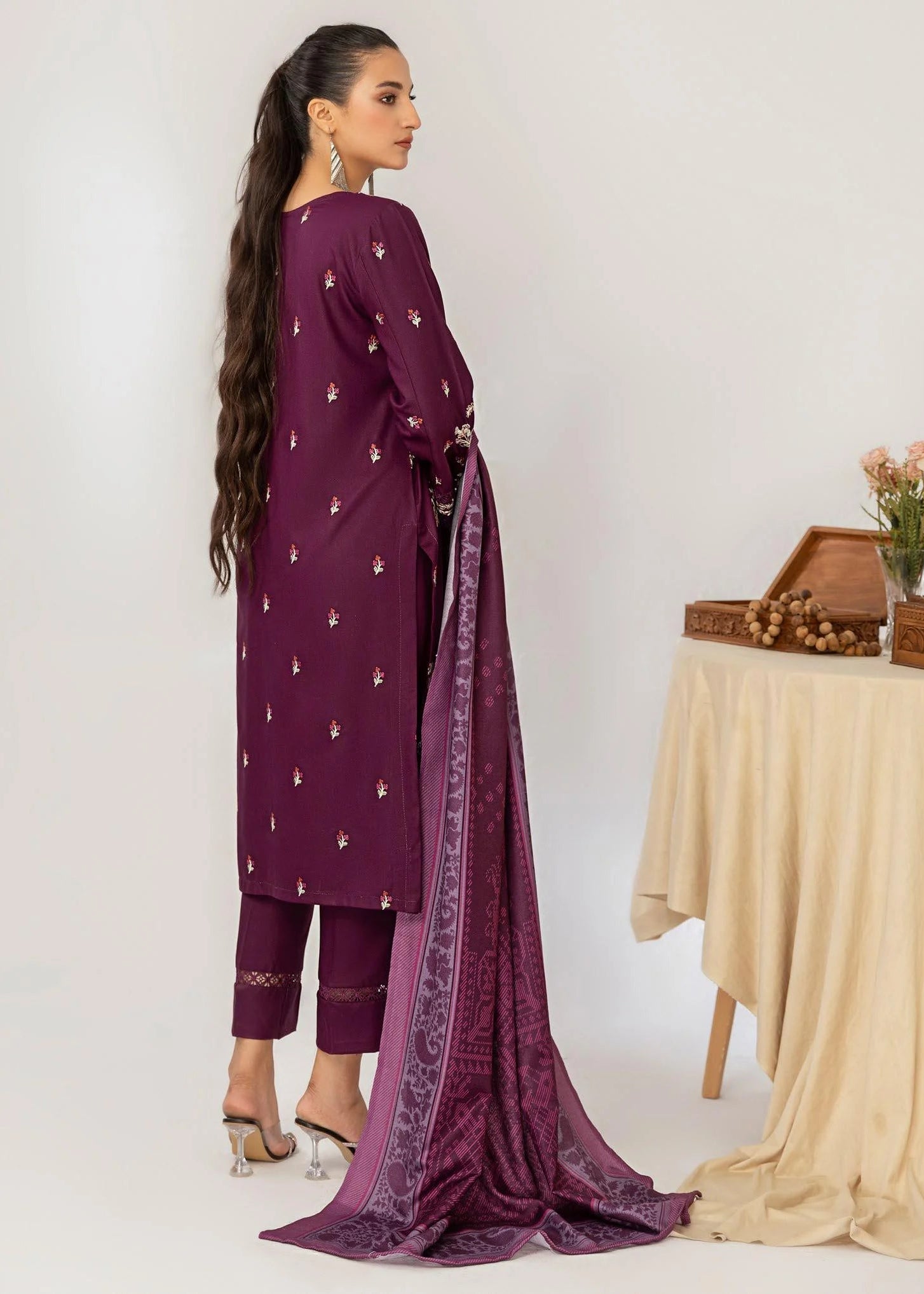 Purple embroidered outfit with a table and plant in the background
