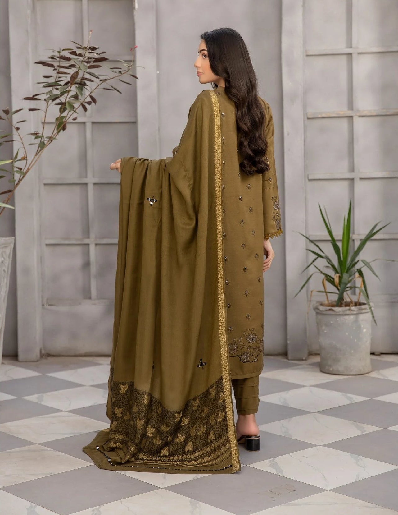 Woman modeling a green traditional outfit with a dupatta in a checkered room.