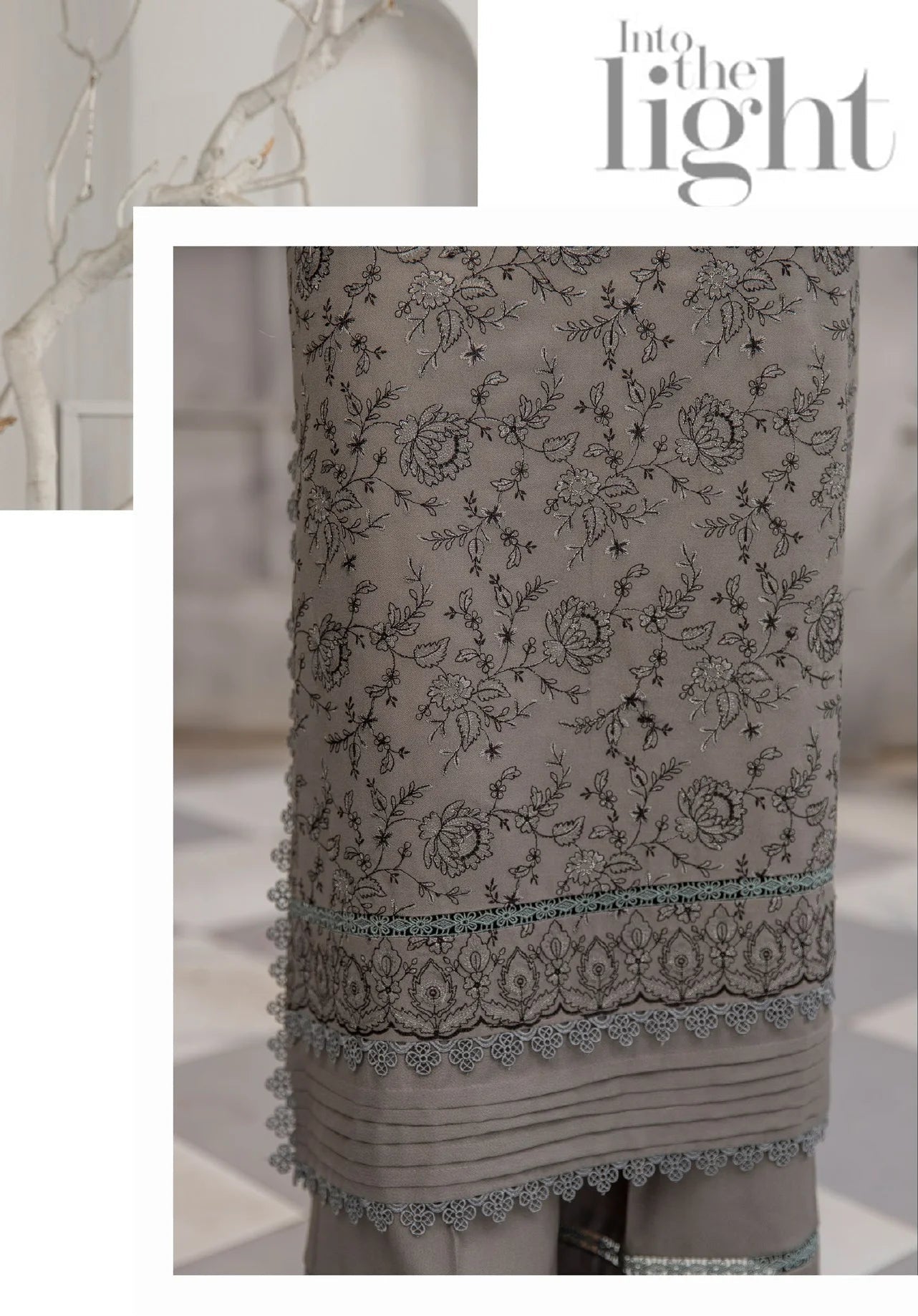 Woman in a gray traditional outfit with floral patterns, standing in a room with decorative elements.