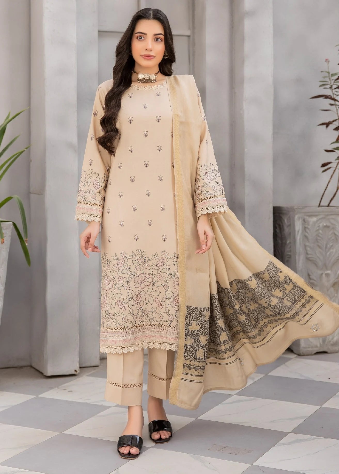 Woman wearing a beige embroidered outfit with a matching dupatta, standing against a neutral background.