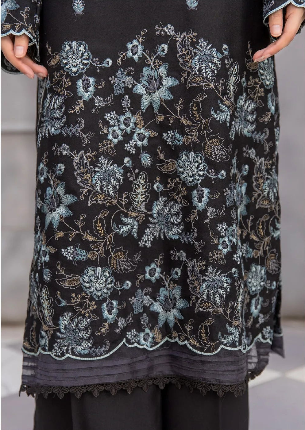 Woman wearing a black floral dress holding a plant, with a close-up of the dress's pattern.