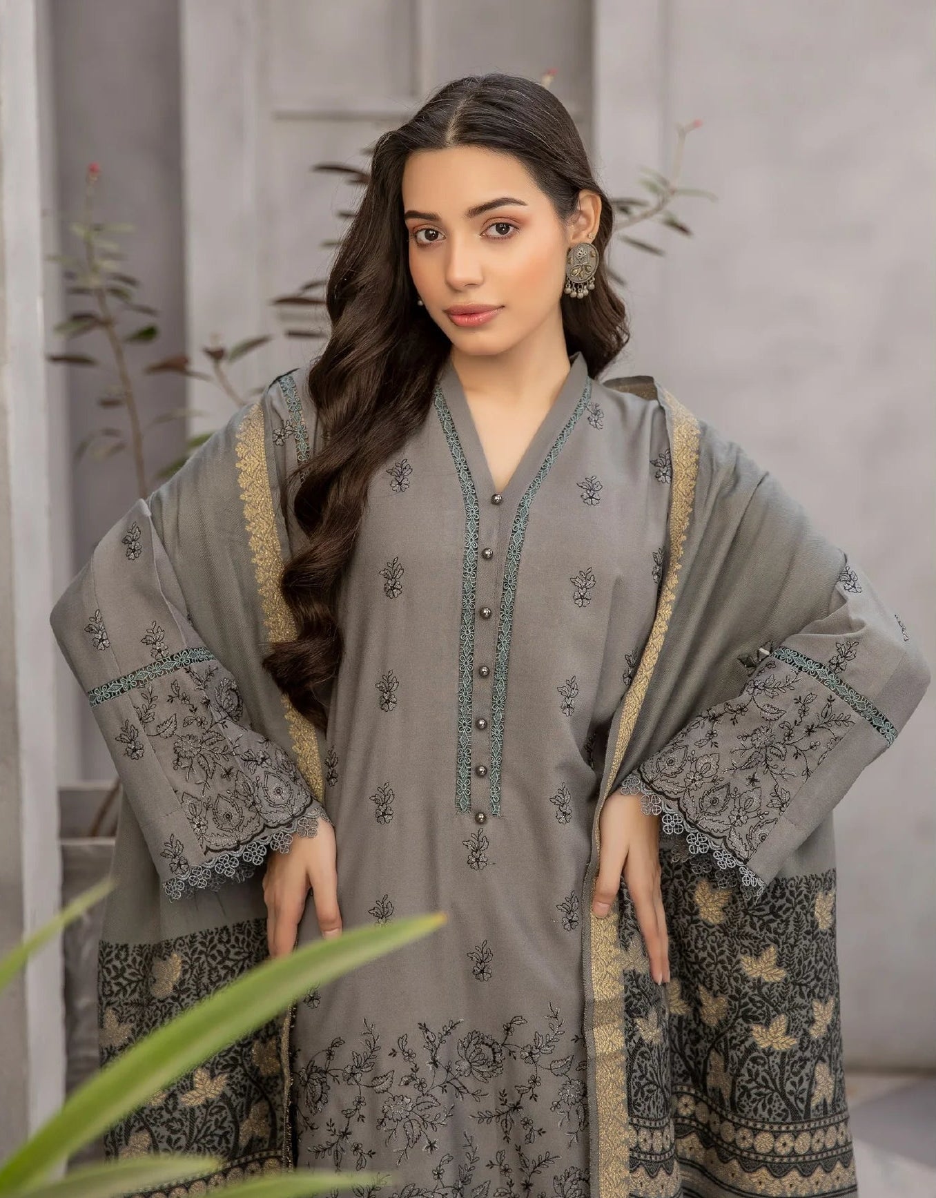 Woman wearing a gray traditional outfit with intricate patterns in an indoor setting.