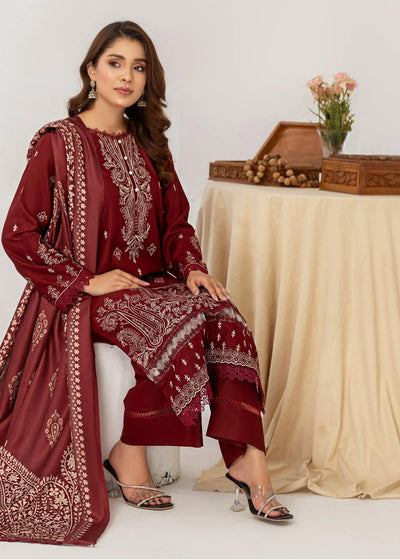 Woman in a red traditional outfit sitting next to a table with a beige cloth and a small plant on a white background