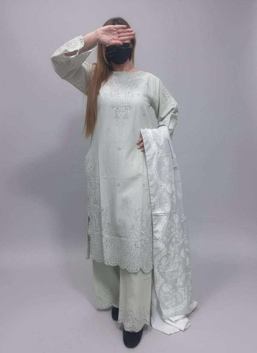 A Women wearing a light-colored embroidered outfit against a green background