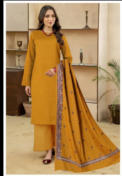 Woman wearing a mustard yellow outfit with a matching dupatta in an indoor setting.