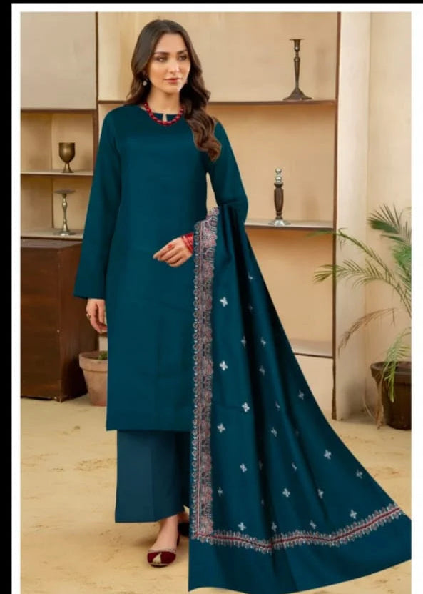 Woman wearing a teal traditional outfit with a matching dupatta in a room setting.