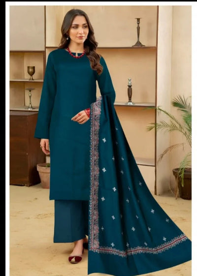 Woman wearing a teal traditional outfit with a matching dupatta in a room setting.
