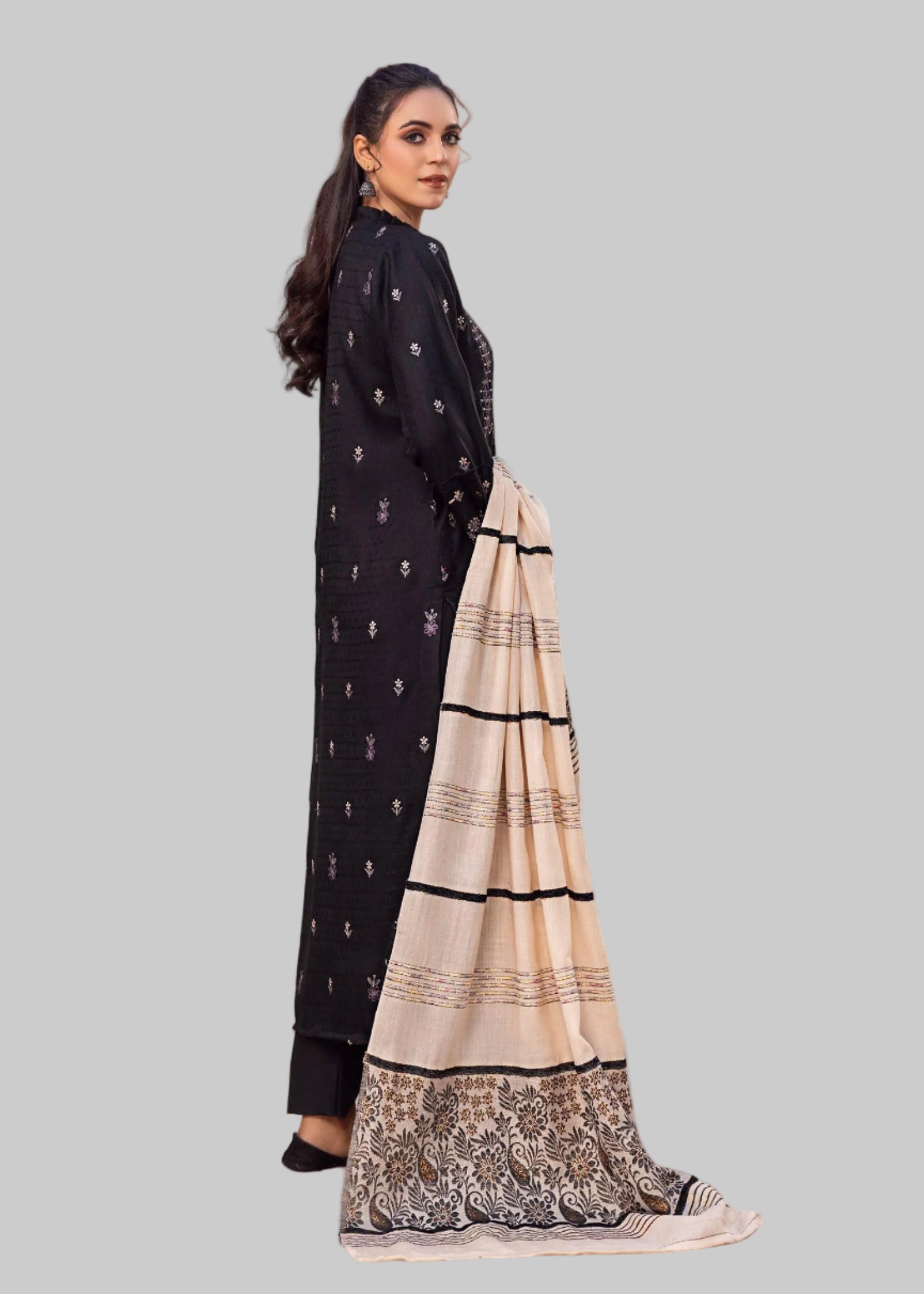 Woman in a black and white traditional outfit standing in a Studio room with a painting of a garden.