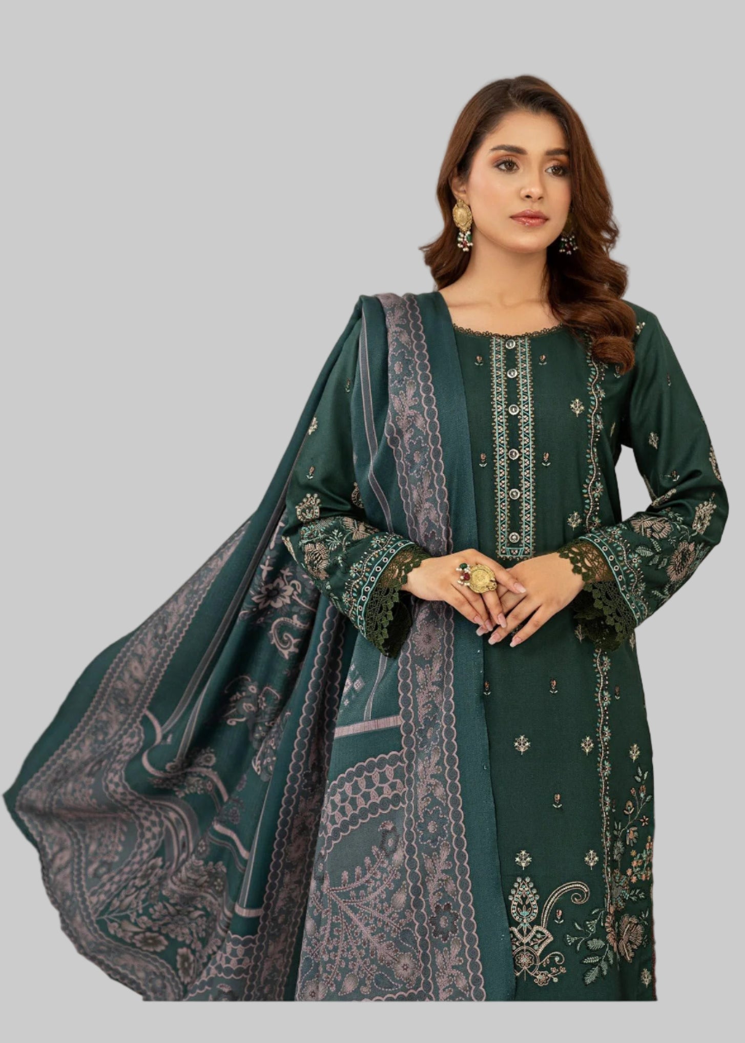 Woman in a green traditional outfit standing next to a table with a red tablecloth and floral arrangement.