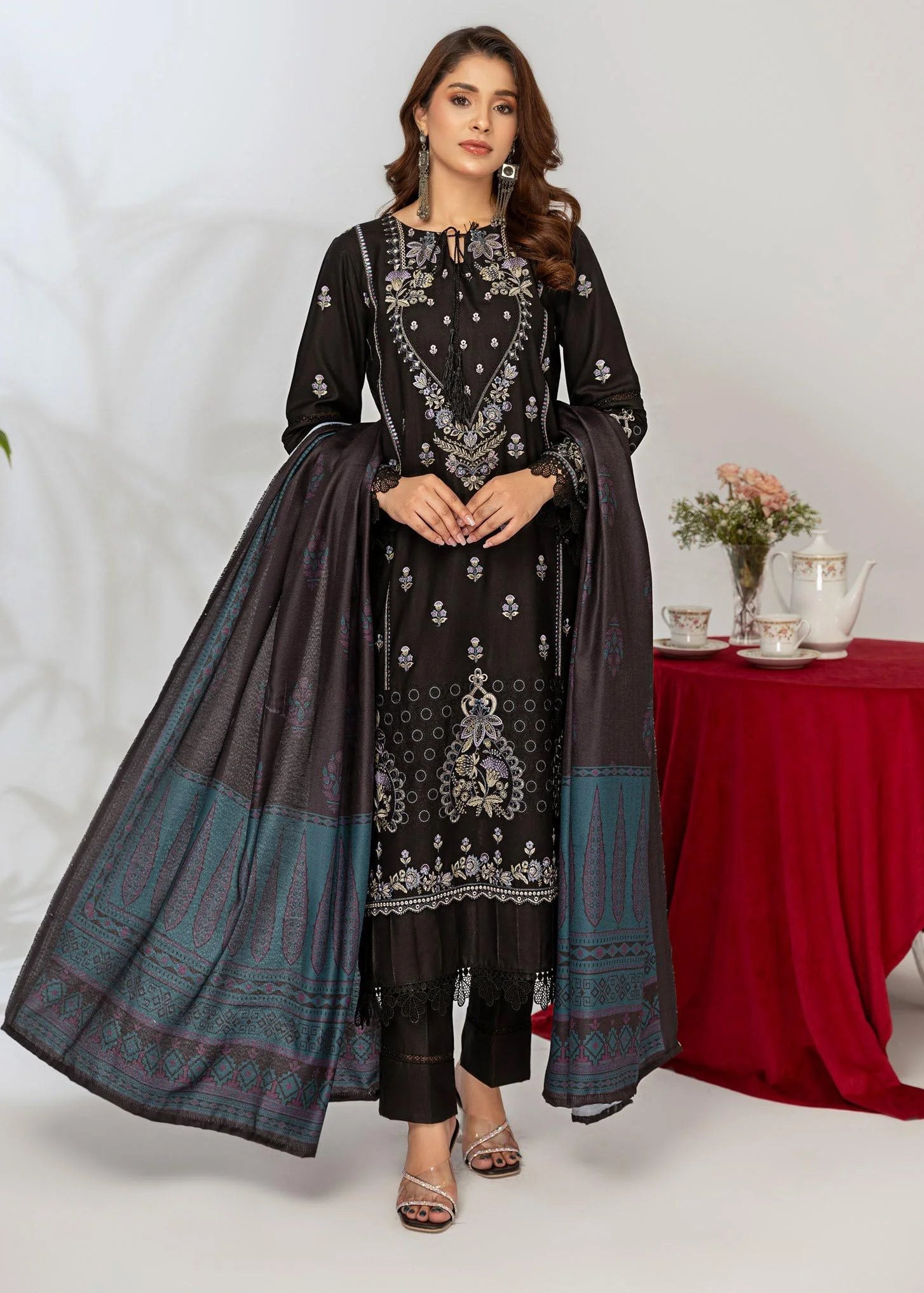 Woman in black and blue traditional outfit with a framed photo of herself at a tea party.
