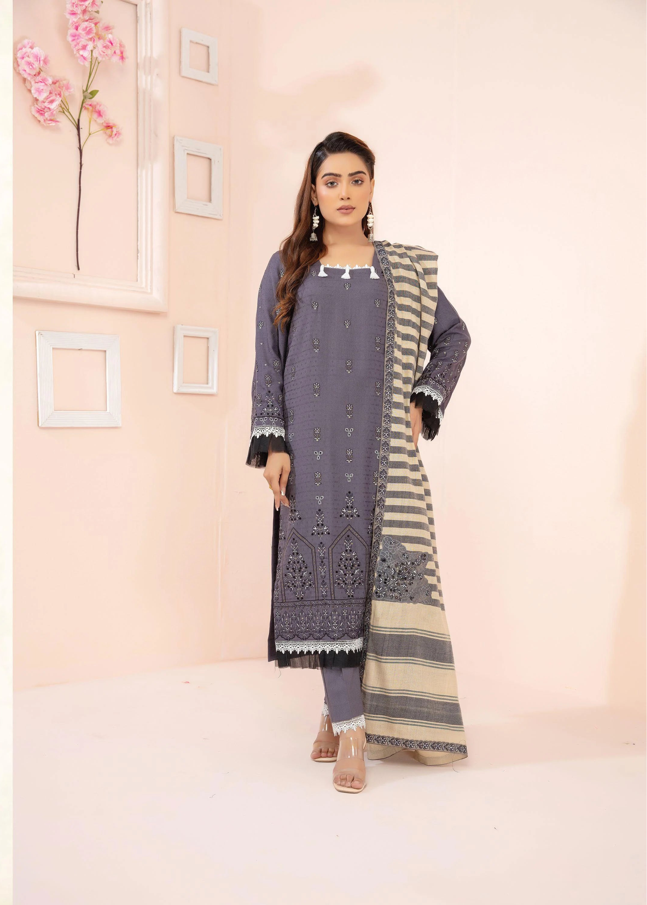 Woman wearing a gray and black patterned outfit with a matching jacket in a minimalistic setting.