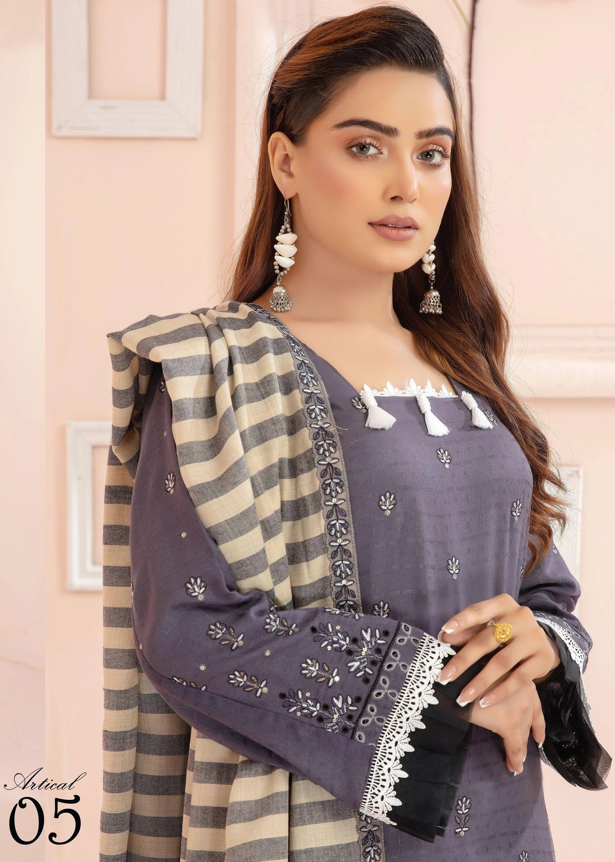 Two women wearing matching outfits with a striped shawl against a light pink background.