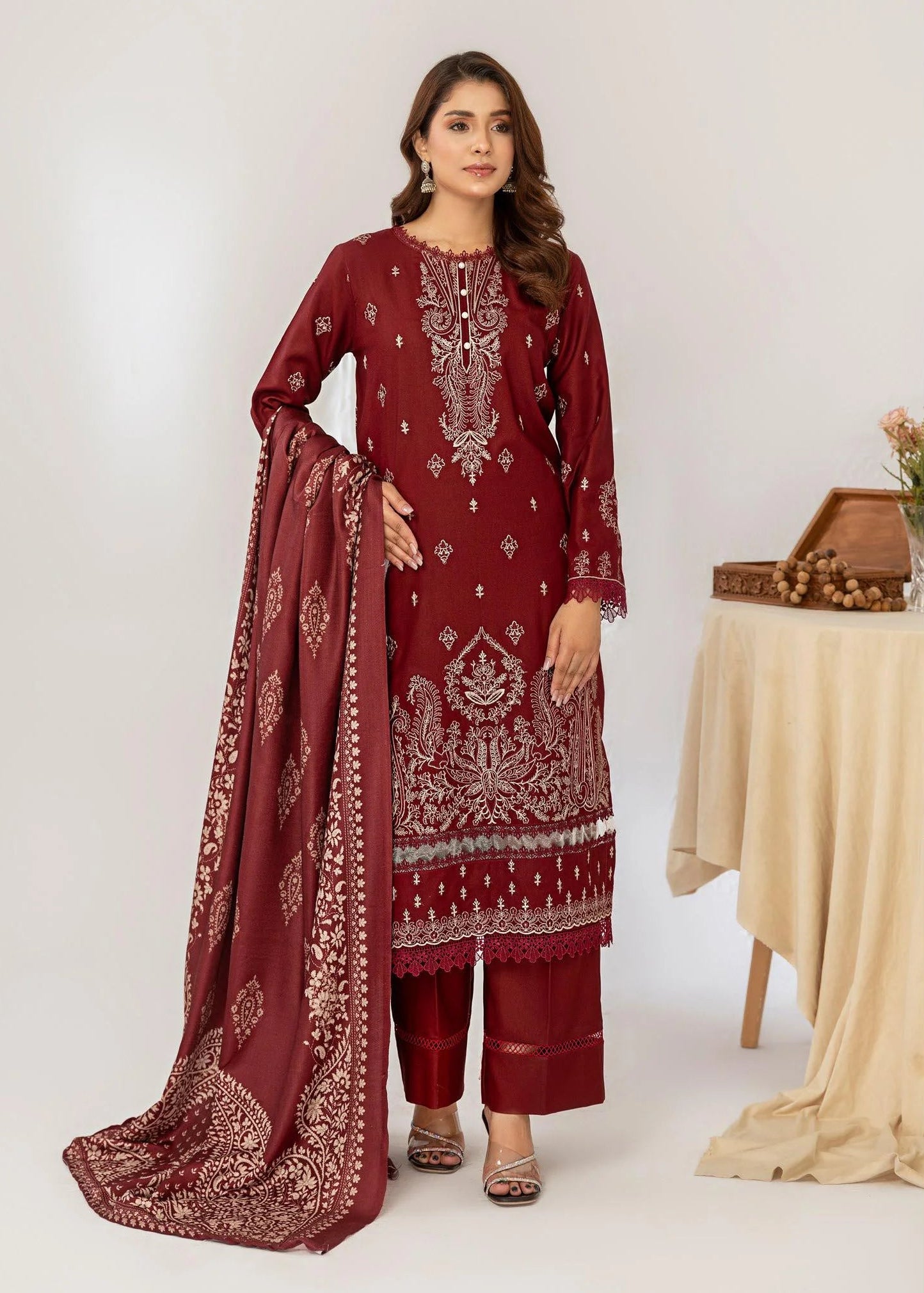 Woman wearing a maroon embroidered outfit with a matching dupatta on a white background.