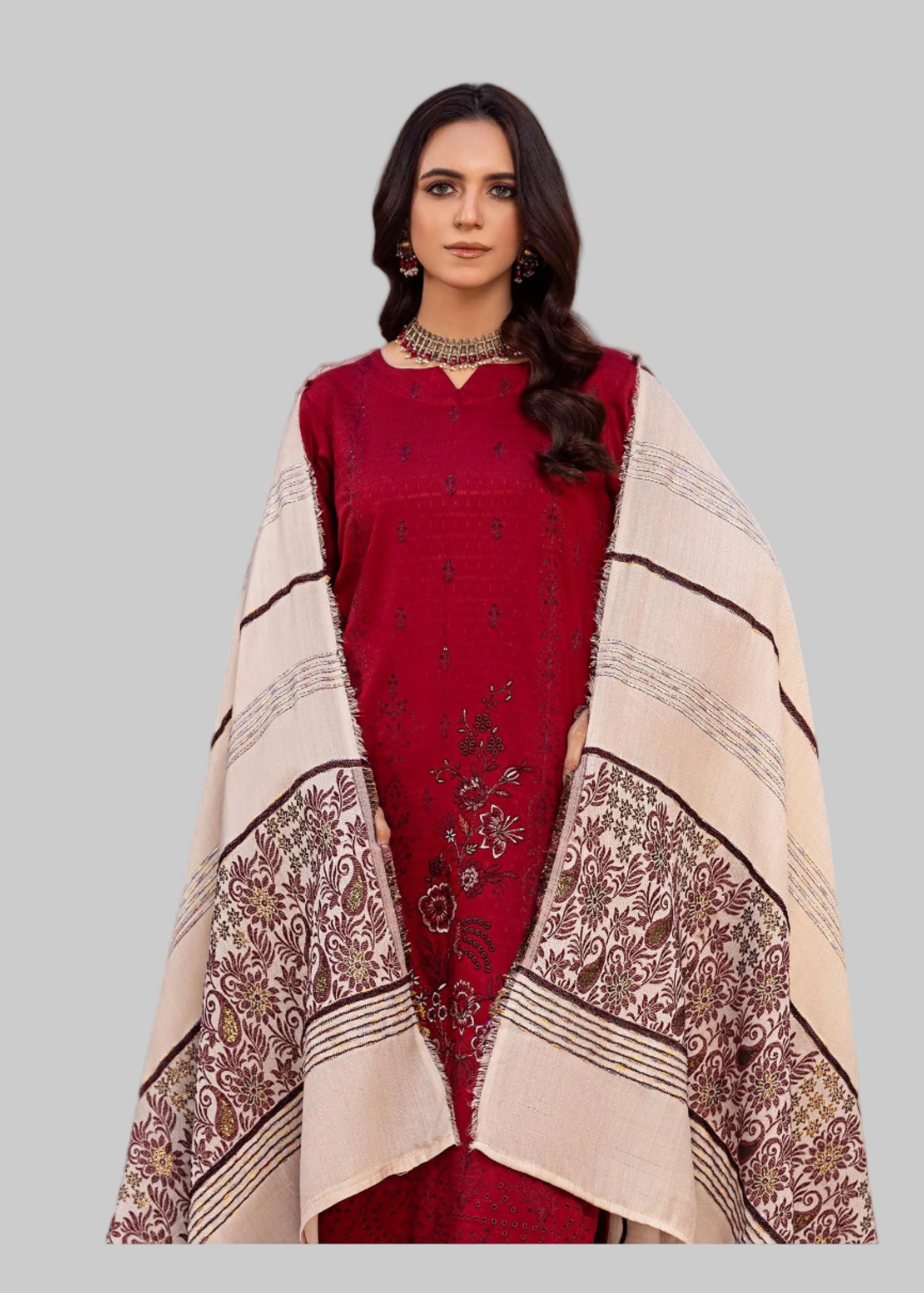 Woman in a red traditional outfit with a patterned shawl standing in a decorated room.