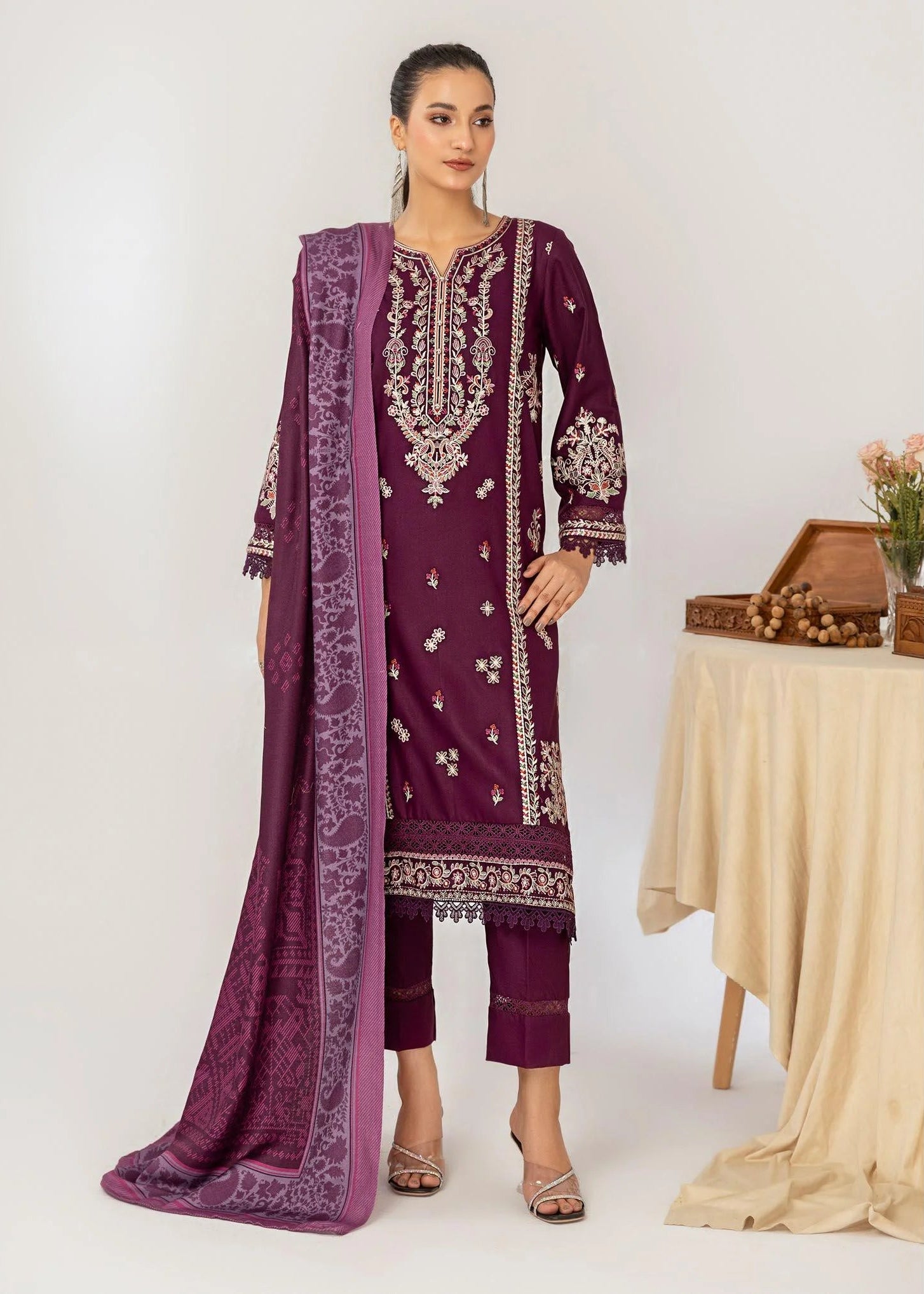 Woman wearing a purple embroidered outfit with a white background