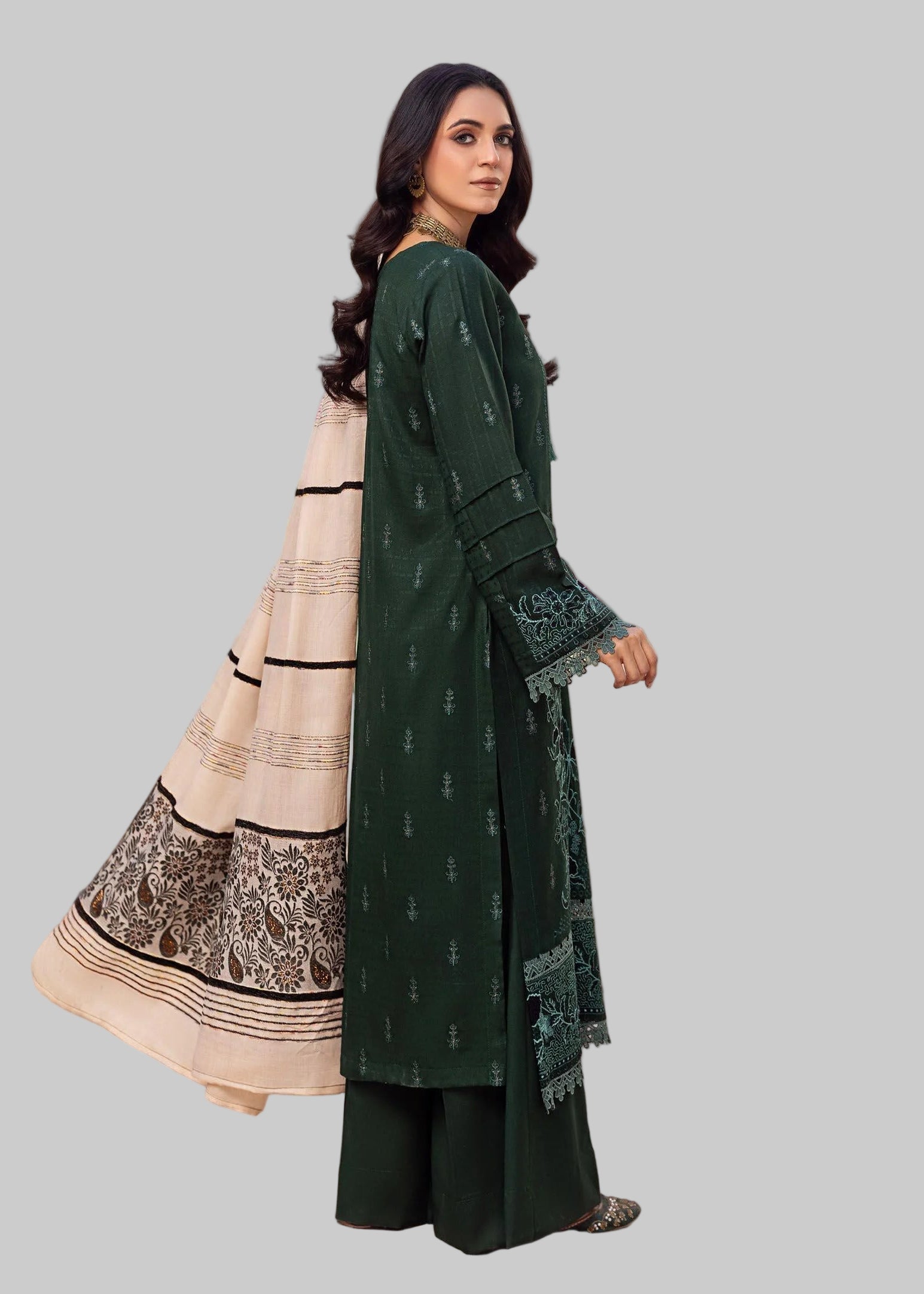 Woman modeling a traditional outfit with a green and beige dress in a Studio room.