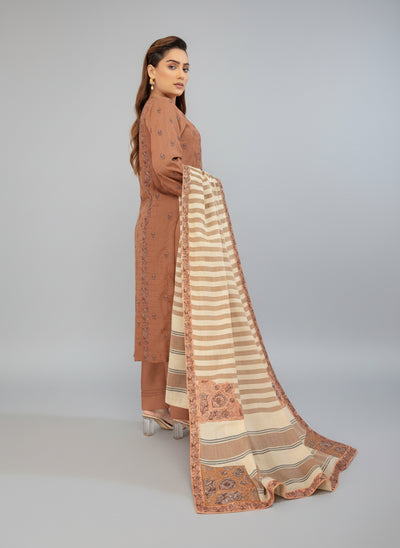 Woman modeling a brown and beige traditional outfit with a scarf in a studio room.