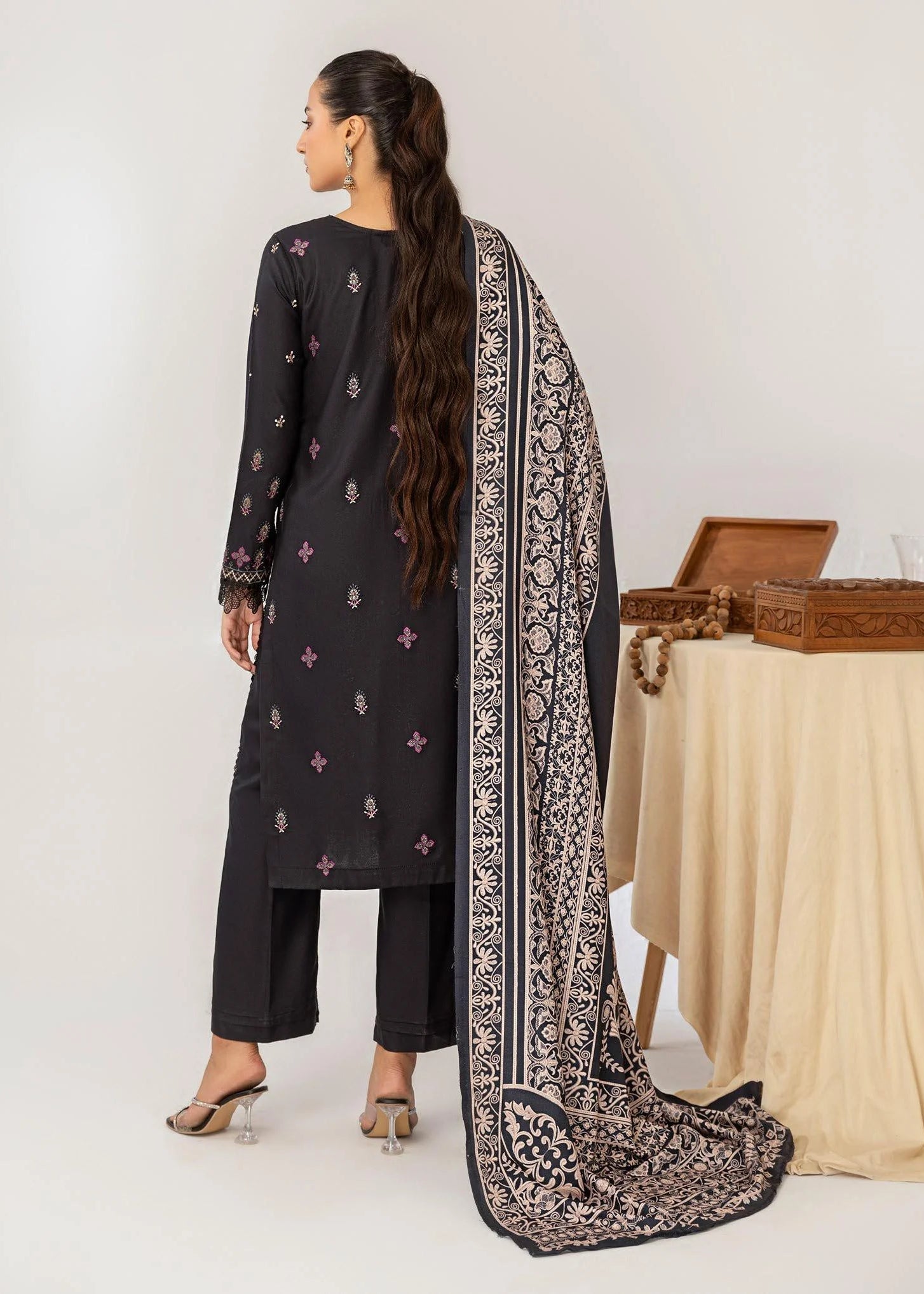 Woman wearing a black embroidered outfit with a matching scarf, with 'Vogue' branding.