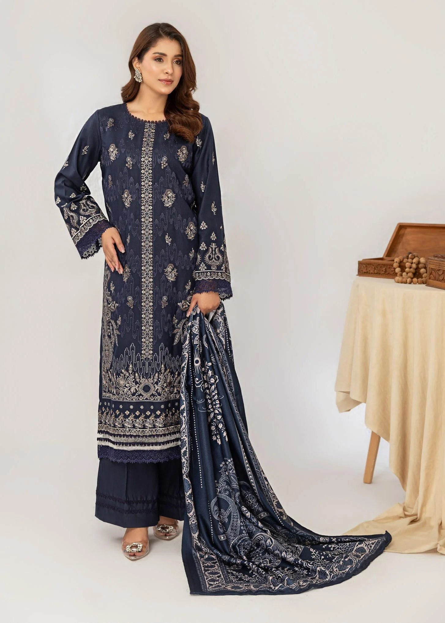 Woman wearing a navy blue embroidered outfit with a matching dupatta on a white background