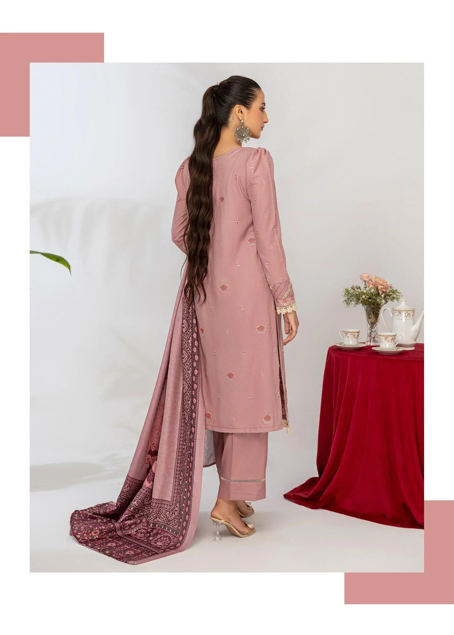 Woman wearing a pink traditional outfit with a matching dupatta, standing in front of a white background.